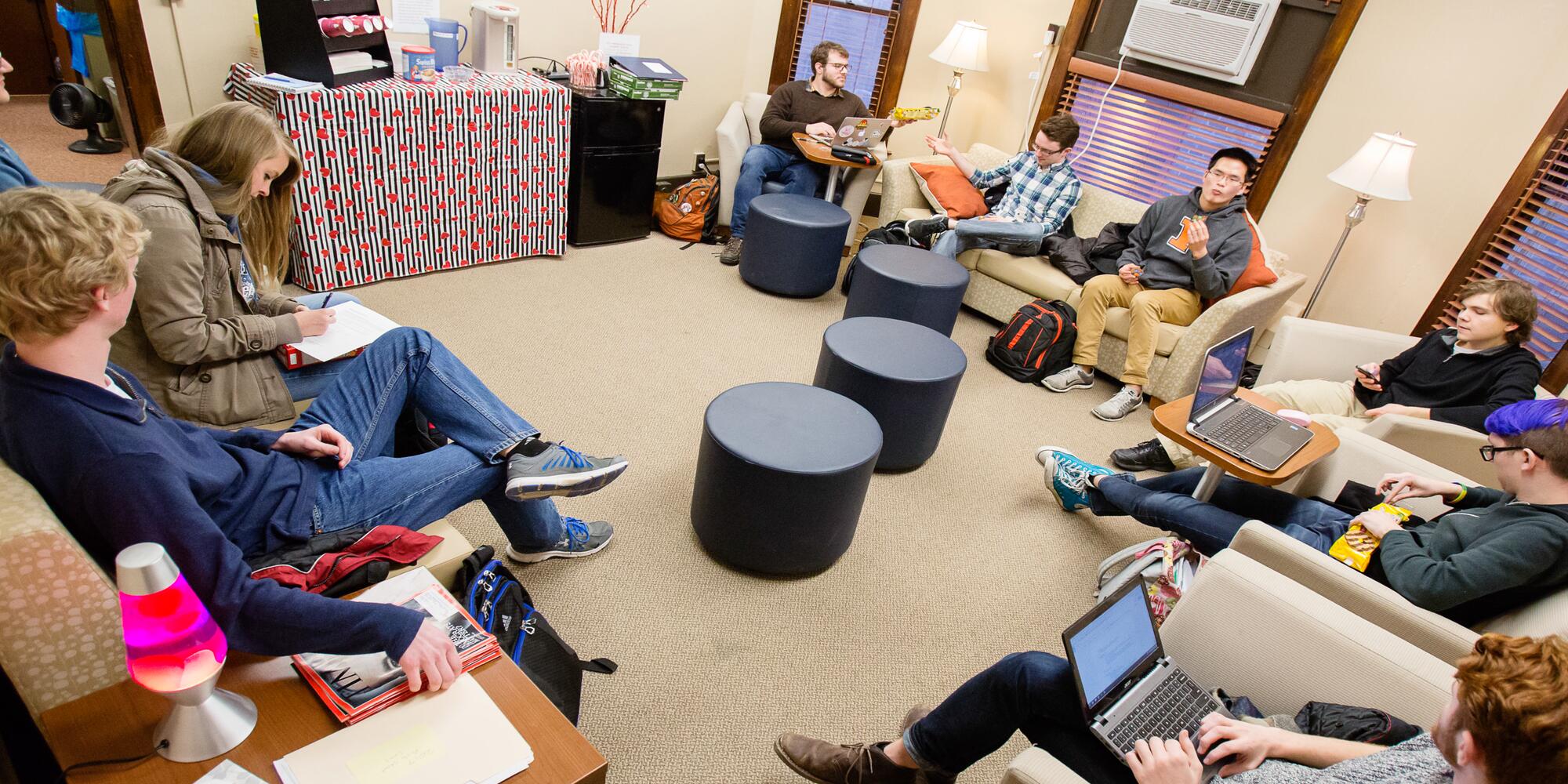 A group of students and a facilitator sitting in a circle having a discussion.